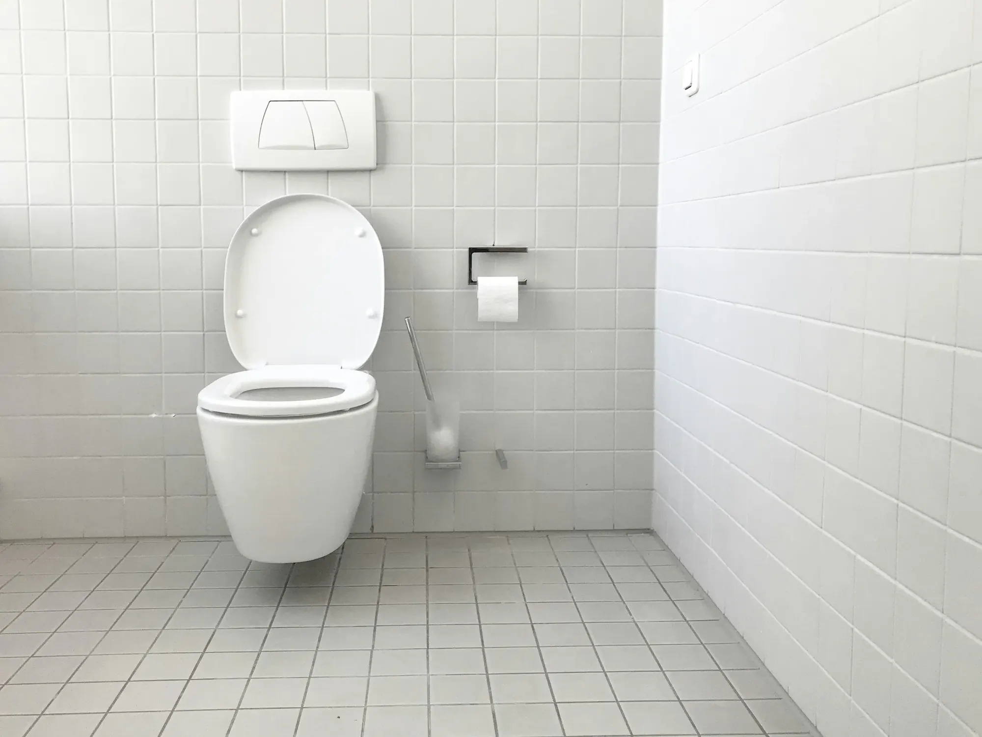 A clean white-tiled commercial restroom